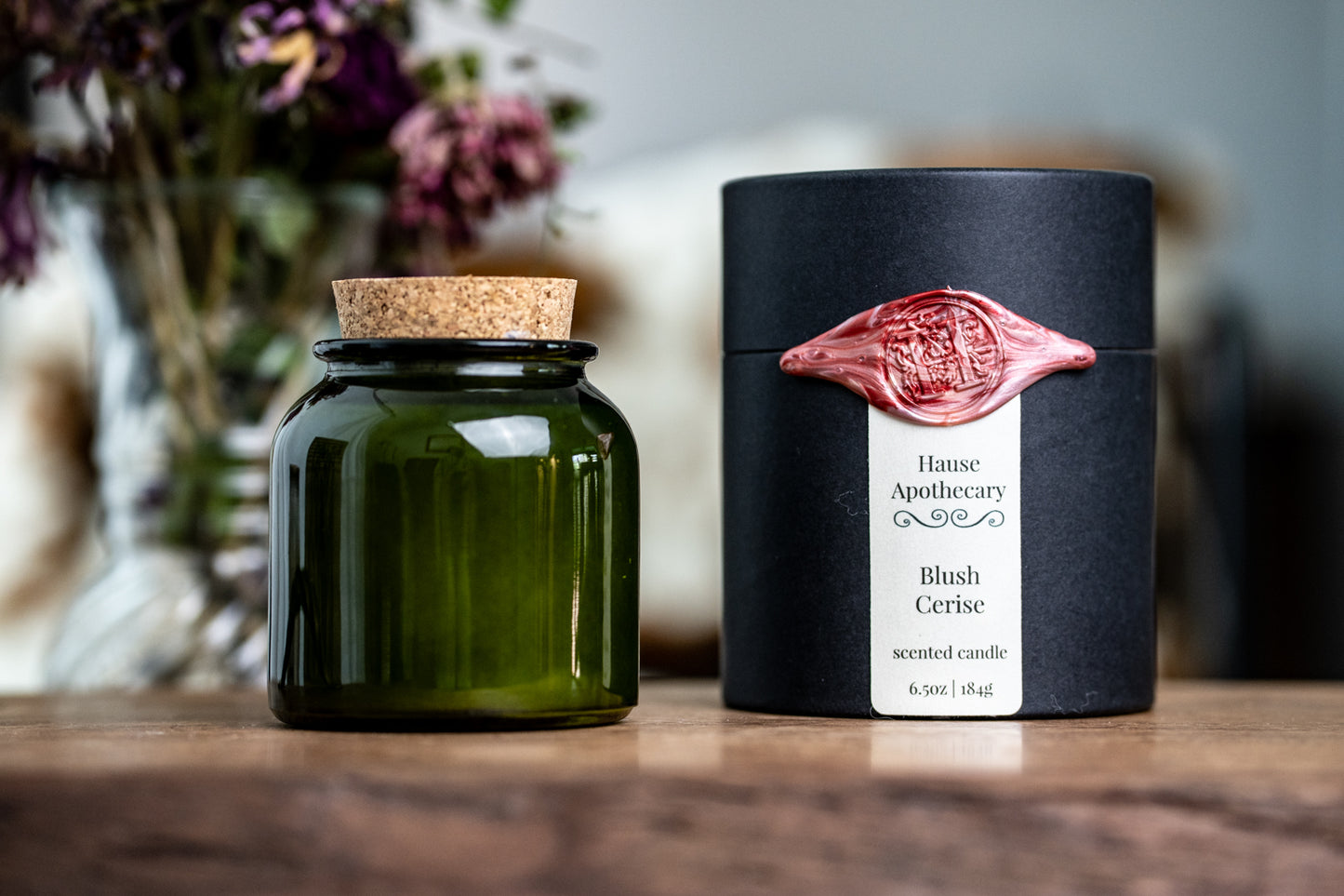green glass jar candle in black kraft tube packaging with wax seal